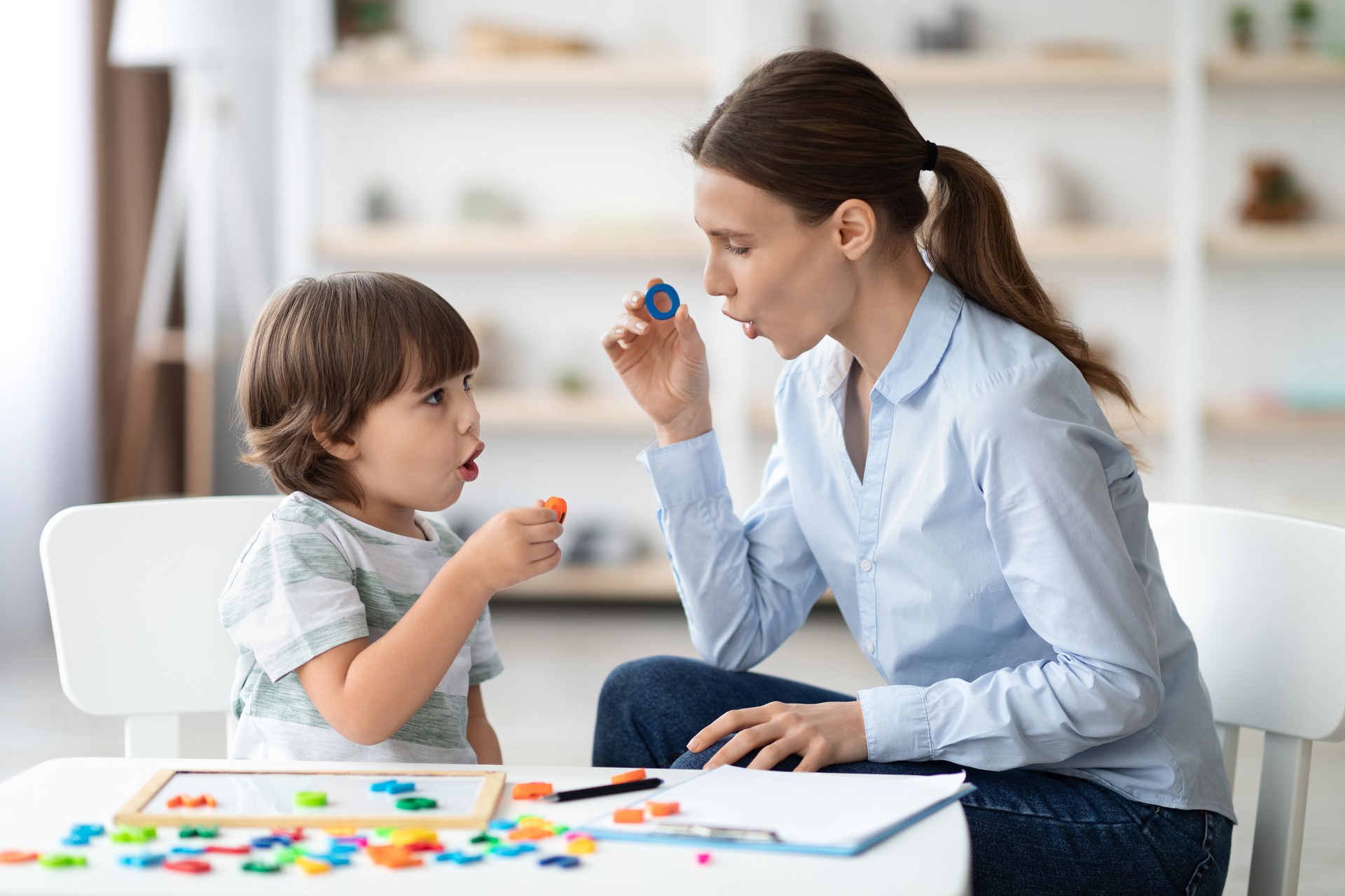 Terapeuta del habla femenina que cura los problemas e impedimentos del niño. Niño pequeño aprendiendo la letra O con tutor privado